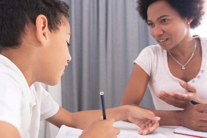 A parent helping a child with homework at a table