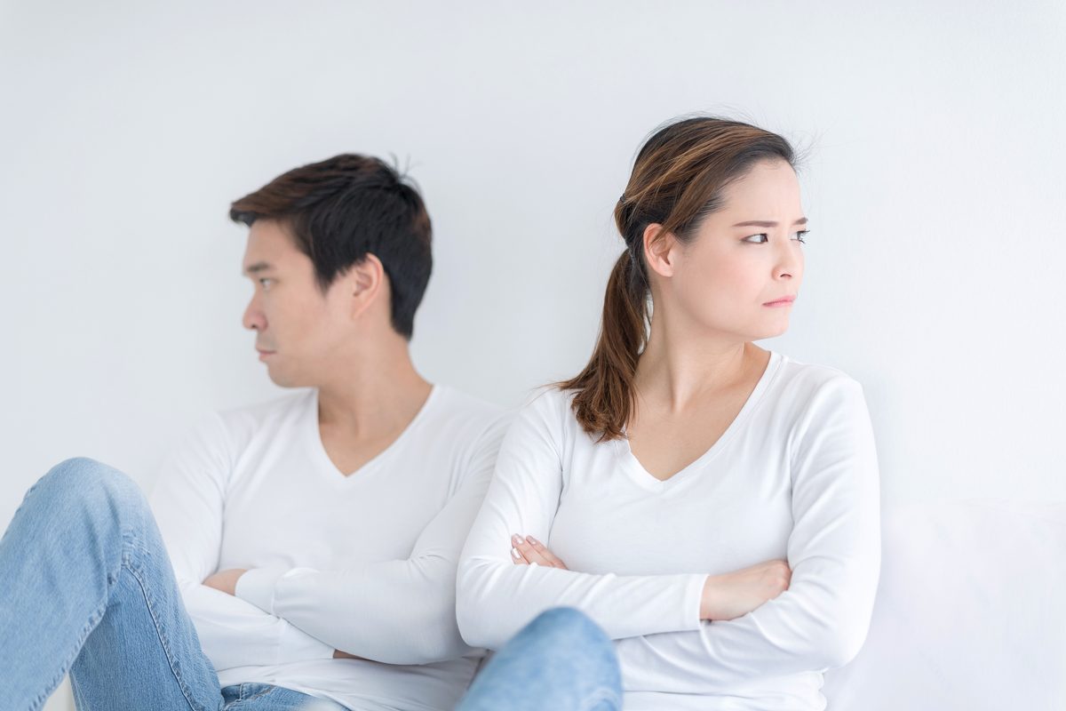 A couple sitting back to back, looking away from each other